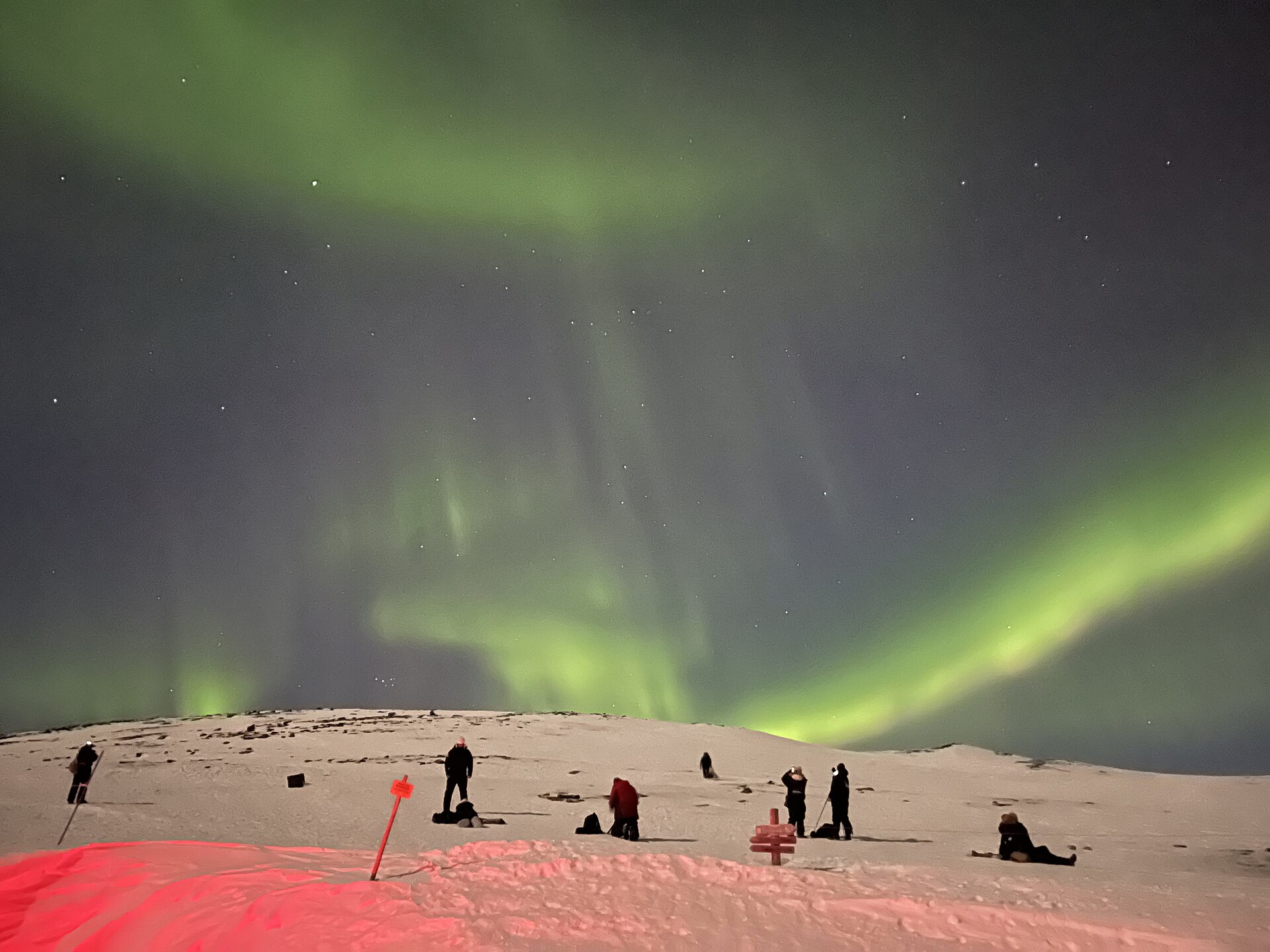 Fotógrafos trabajando la aurora boreal desde una ladera nevada en Abisko